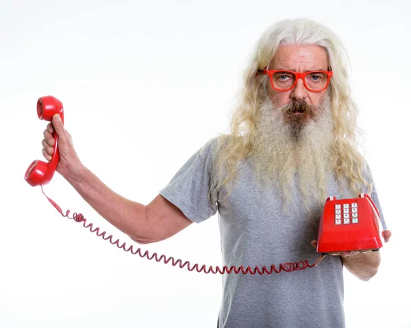 Studio shot van senior bebaarde man houdt van oude telefoon terwijl lo — Stockfoto