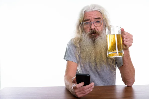 Studio shot van senior bebaarde man met mobiele telefoon en glas — Stockfoto