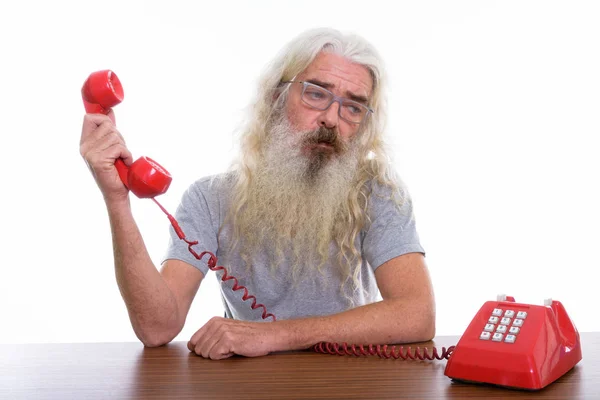 Studio shot van senior bebaarde man houdt van oude telefoon terwijl lo — Stockfoto