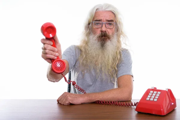 Estúdio tiro de homem barbudo sênior dando telefone velho em madeira — Fotografia de Stock