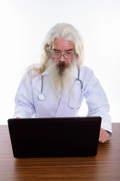 Studio dizüstü bilgisayar üzerinde ahşap kullanarak üst düzey sakallı adam doktor doz — Stok fotoğraf