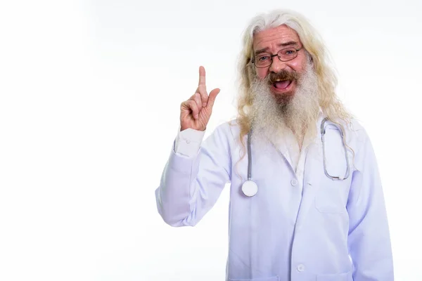 Estúdio tiro de homem barbudo sênior feliz médico sorrindo enquanto poi — Fotografia de Stock