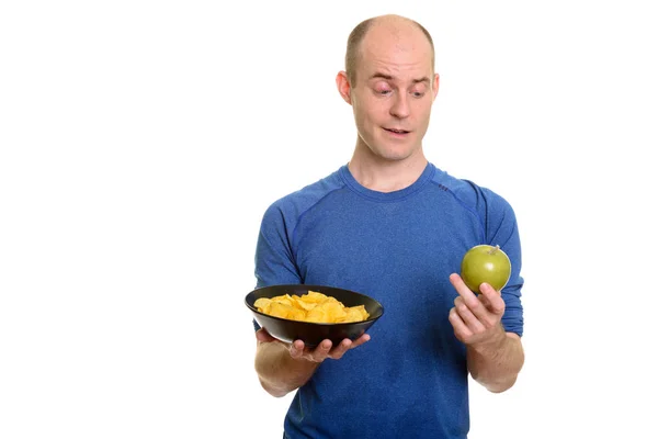 Bald Caucasian man  choosing between bowl of potato chips and gr — Stock Photo, Image