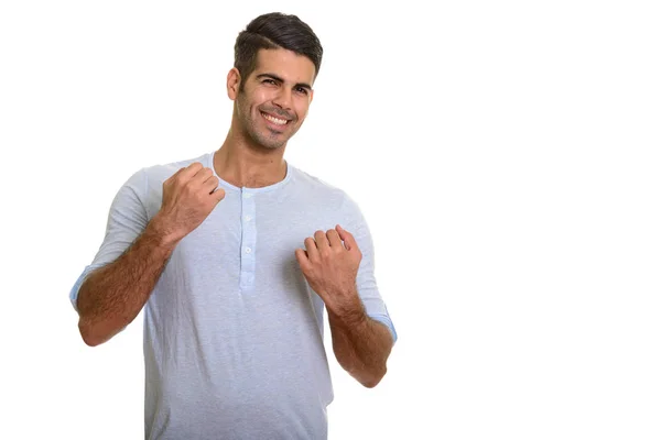 Młody szczęśliwy Perski mężczyzna uśmiechnięty i z podniesionymi ramionami — Zdjęcie stockowe