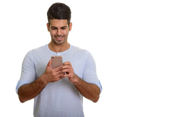 Young happy Persian man smiling and using mobile phone — Stock Photo, Image