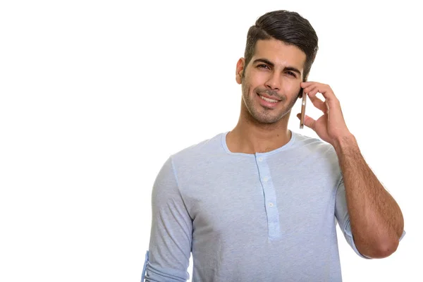 Młody szczęśliwy Perski człowiek uśmiecha się i rozmawia przez telefon komórkowy — Zdjęcie stockowe