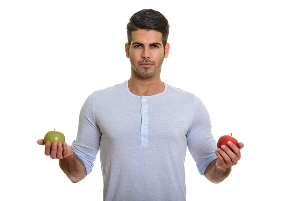 Joven hombre persa guapo sosteniendo manzana roja y verde — Foto de Stock