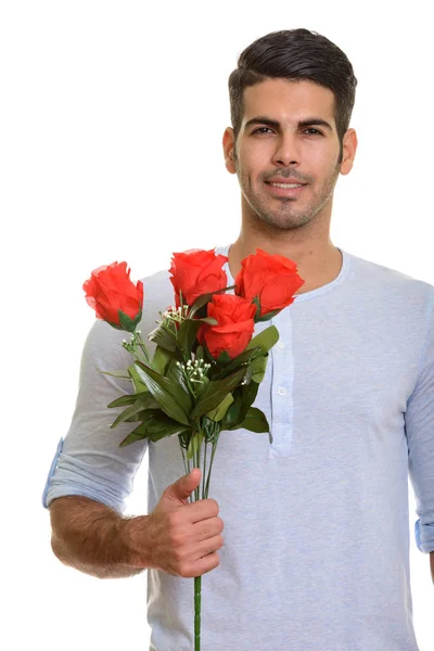 Joven hombre persa feliz sonriendo mientras sostiene rosas rojas listo fo — Foto de Stock