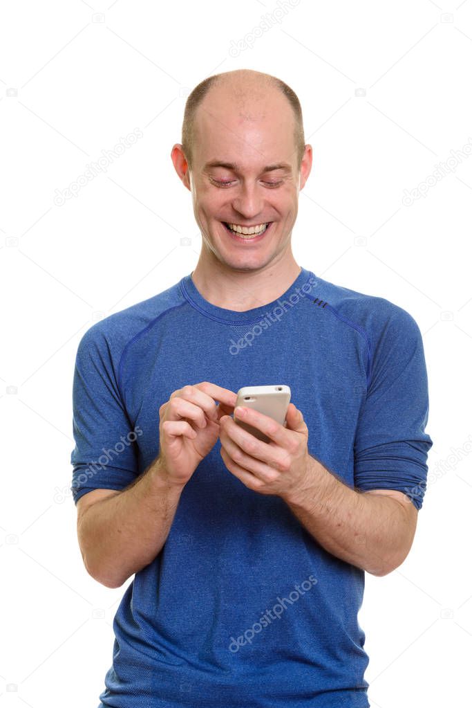 Happy bald Caucasian man smiling and using mobile phone