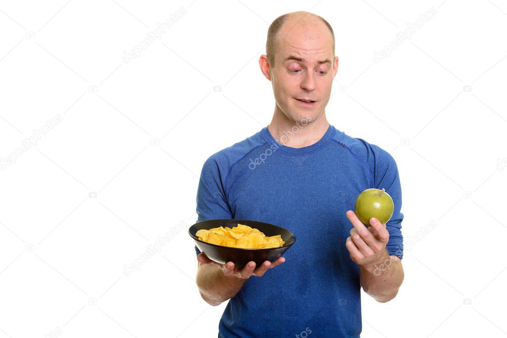 Bald Caucasian man  choosing between bowl of potato chips and gr