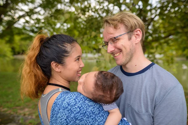 Multietniska ung familj limning tillsammans på park — Stockfoto