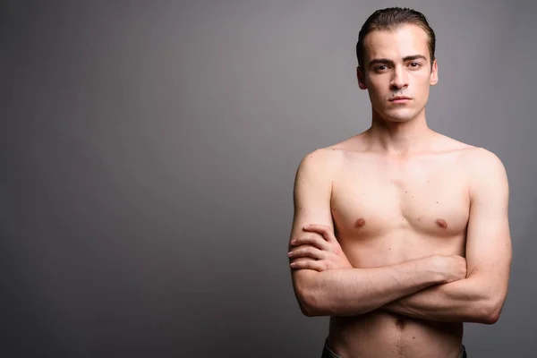 Jovem bonito homem sem camisa com braços cruzados contra fundo cinza — Fotografia de Stock