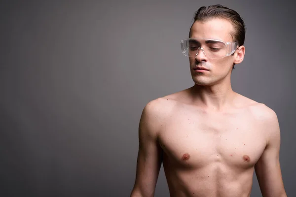 Jonge knappe man shirtless dragen van beschermende glassesagainst grijze achtergrond — Stockfoto