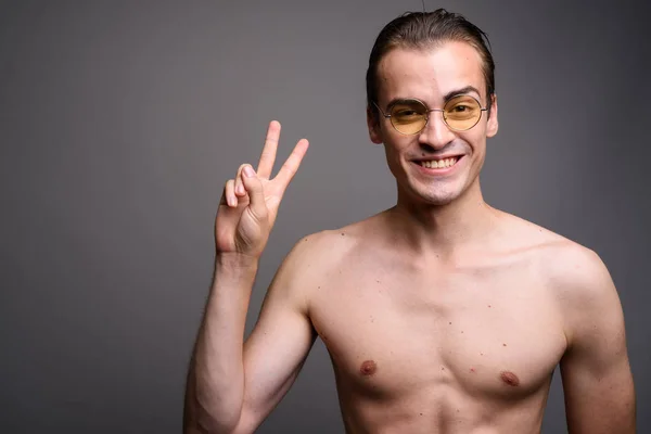 Joven hombre guapo sin camisa haciendo señal de paz sobre fondo gris — Foto de Stock