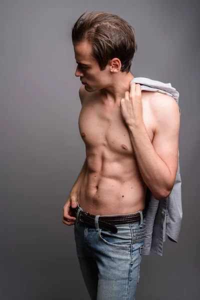 Junger gutaussehender Mann ohne Hemd vor grauem Hintergrund — Stockfoto