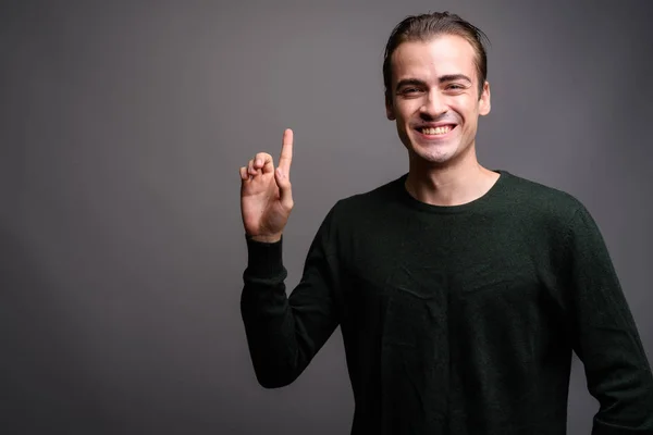 Jovem homem feliz apontando o dedo para cima e mostrando espaço de cópia — Fotografia de Stock