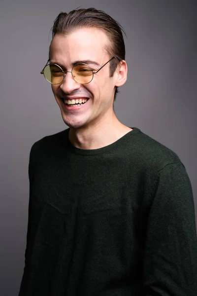 Young handsome man laughing against gray studio background — Stock Photo, Image