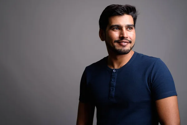 Young handsome bearded Persian man against gray background — Stock Photo, Image