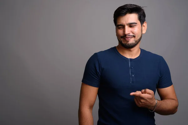 Joven guapo barbudo persa hombre sobre fondo gris — Foto de Stock