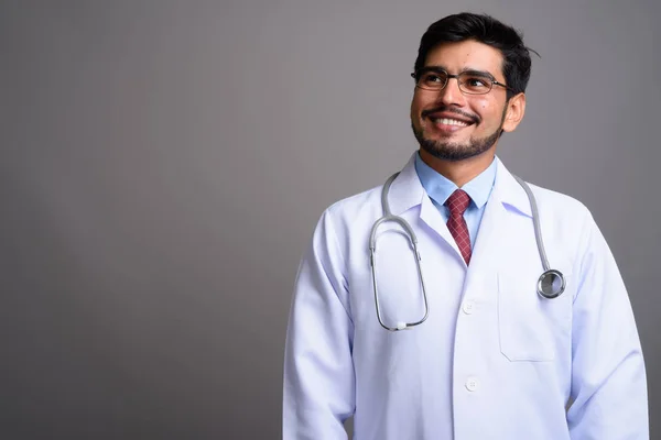 Jovem bonito barbudo persa homem médico contra cinza backgroun — Fotografia de Stock