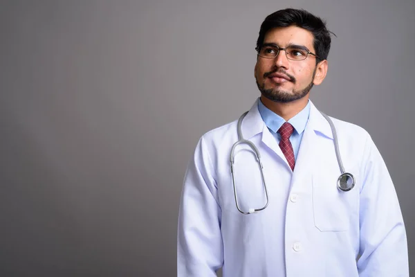 Joven guapo barbudo médico hombre persa contra fondo gris — Foto de Stock