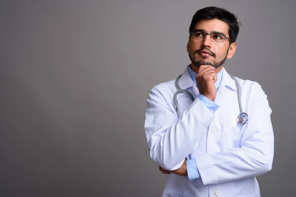 Jovem bonito barbudo persa homem médico contra cinza backgroun — Fotografia de Stock