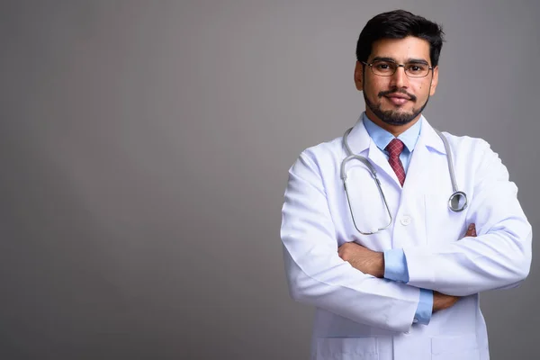 Jovem bonito barbudo persa homem médico contra cinza backgroun — Fotografia de Stock