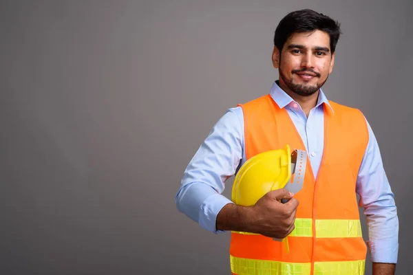 Joven guapo barbudo persa trabajador de la construcción contra g — Foto de Stock