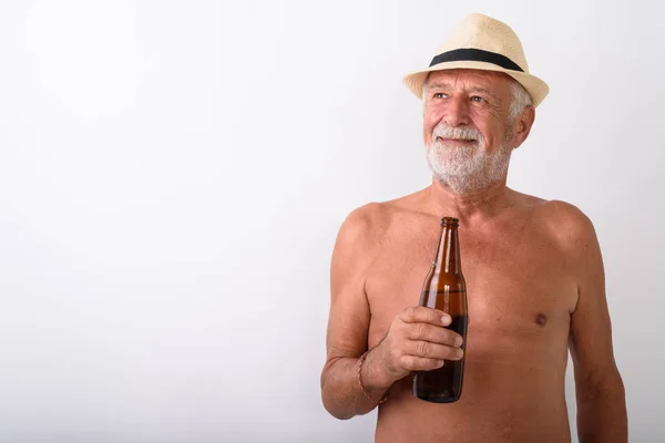 Shirtless uomo anziano in possesso di bottiglia di birra contro sfondo bianco — Foto Stock