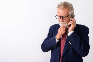 Yakışıklı, yaşlı, sakallı iş adamının cep telefonuyla beyaz arka planda konuşurken çekilmiş bir fotoğrafı.