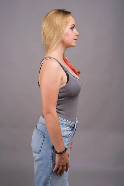 灰色の背景灰色ノースリーブ トップを着ている金髪の若い美しい女性のスタジオ撮影 — ストック写真
