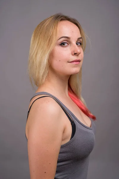 Joven hermosa mujer con cabello rubio sobre fondo gris — Foto de Stock