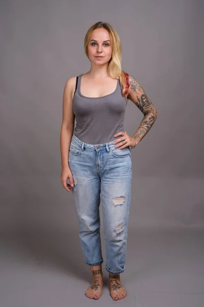 Junge schöne Frau mit blonden Haaren vor grauem Hintergrund — Stockfoto