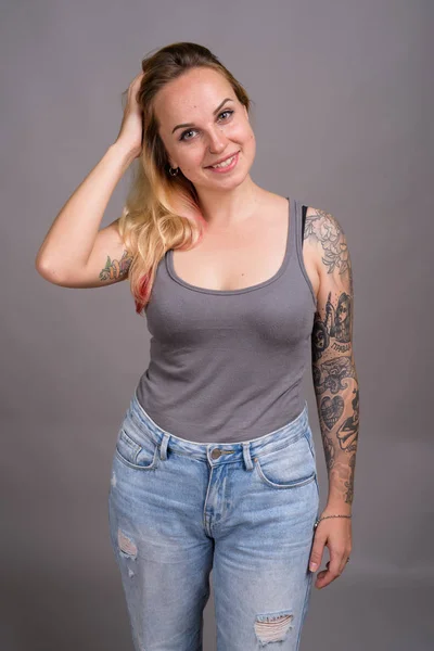 Junge schöne Frau mit blonden Haaren vor grauem Hintergrund — Stockfoto