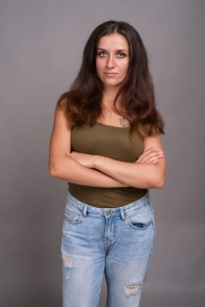 Portrait of young beautiful woman against gray background — Stock Photo, Image