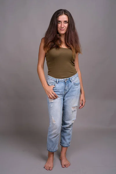 Portrait of young beautiful woman against gray background — Stock Photo, Image