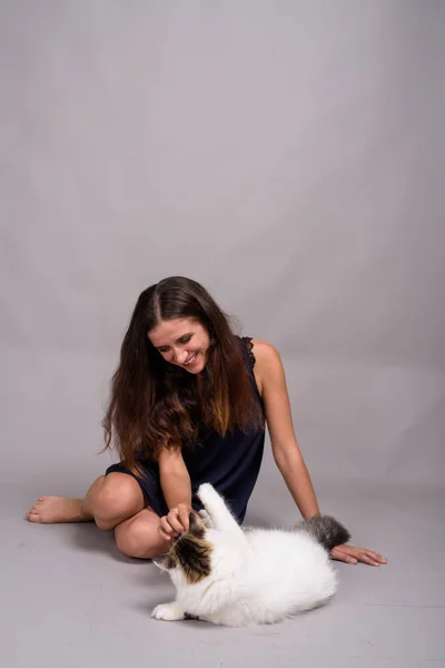 Портрет молодой красивой женщины с котом на сером фоне — стоковое фото