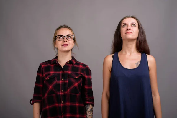 Portrait de deux jeunes belles femmes levant les yeux sur fond gris — Photo