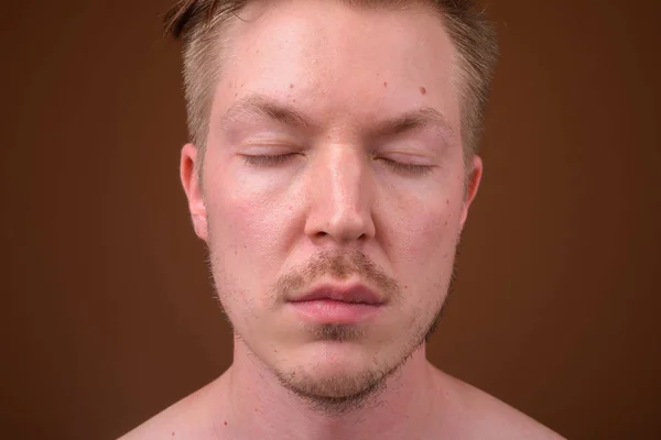 Portret van de jonge man gezicht met ogen dicht tegen bruine achtergrond — Stockfoto