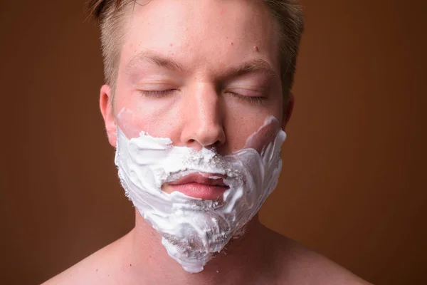 Gezicht van jonge man zijn gezicht scheren met ogen dicht — Stockfoto