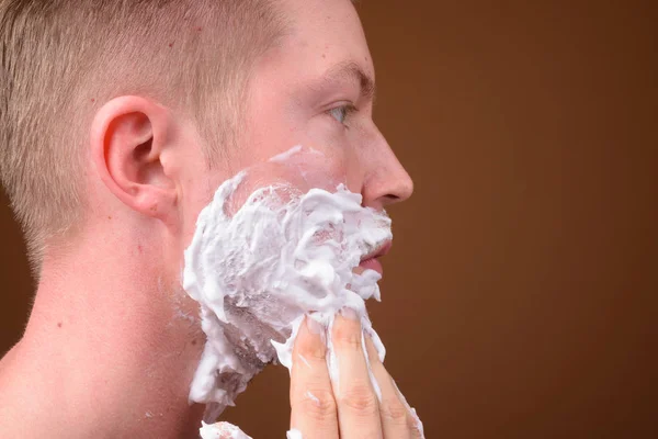 Προβολή προφίλ του νεαρού προσώπου ξύρισμα το πρόσωπό του — Φωτογραφία Αρχείου