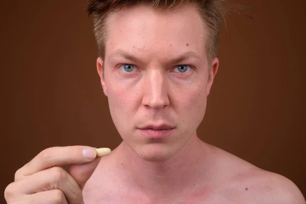 Retrato de jovem sem camisa segurando pílula multi vitamina — Fotografia de Stock