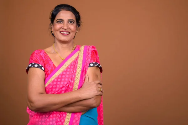 Happy mature beautiful Indian woman smiling with arms crossed — Stock Photo, Image