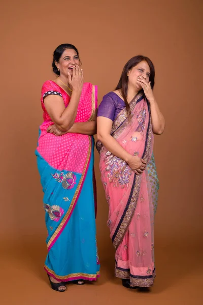 Two mature Indian women wearing traditional clothes and laughing