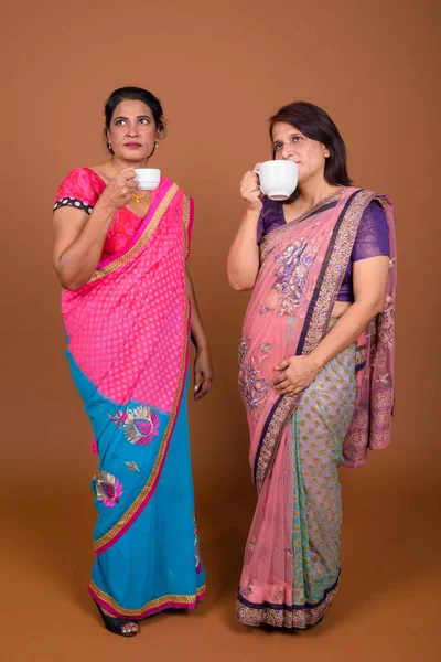 Two mature Indian women drinking coffee or tea