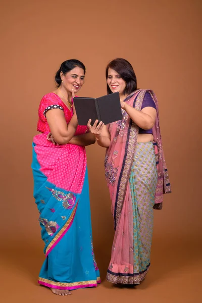 Two mature Indian women reading book together