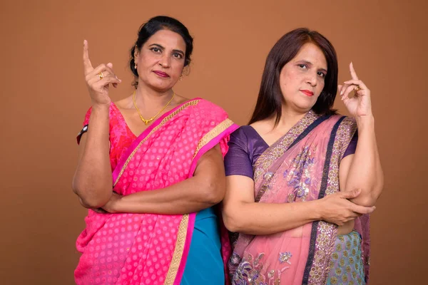 Portrait of two mature Indian women pointing finger up together — Stock Photo, Image