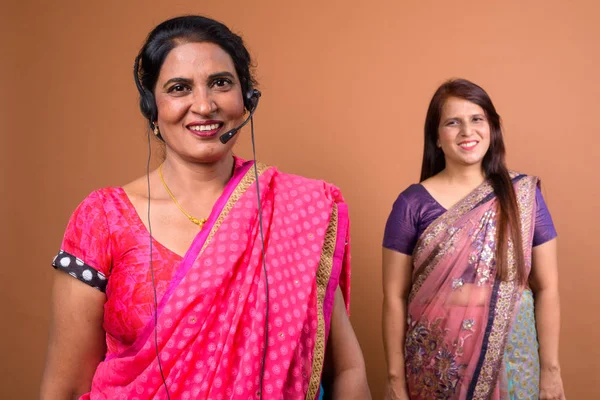 Happy mature Indian woman call center representative wearing headset