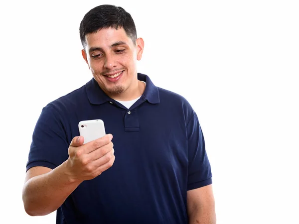 Studio shot of young happy Hispanic man smiling while using mobi — Stock Photo, Image