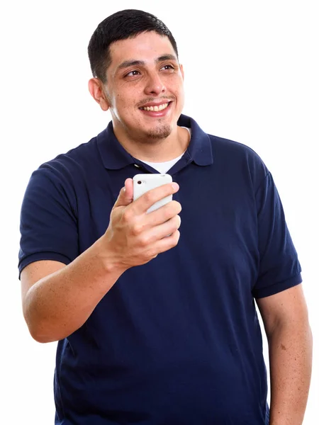 Young happy Hispanic man smiling while holding mobile phone and — Stock Photo, Image